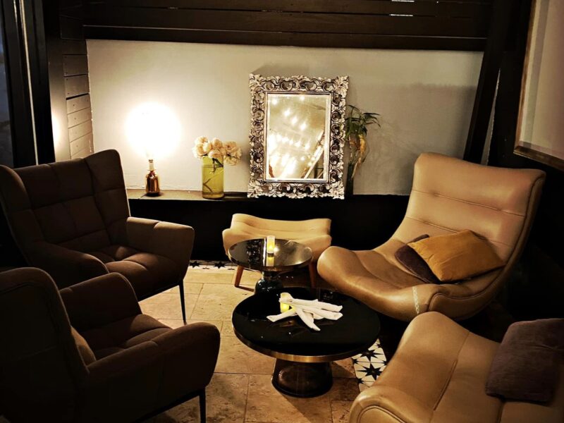 Photo de l'intérieur du 12. Quatre fauteuils encerclent une petite table ronde. La lumière est tamisée.