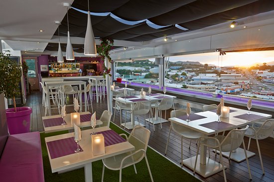 Vue sur la salle du restaurant en toit terrasse. Un coucher de soleil est visible en arrière plan.
bars et restaurants à Nouméa
