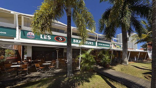 Photo de l'extérieur des 3 Brasseurs,, leur logo est visible sur la devanture. Deux palmiers sont visibles au premier plan. 
bars et restaurants à Nouméa