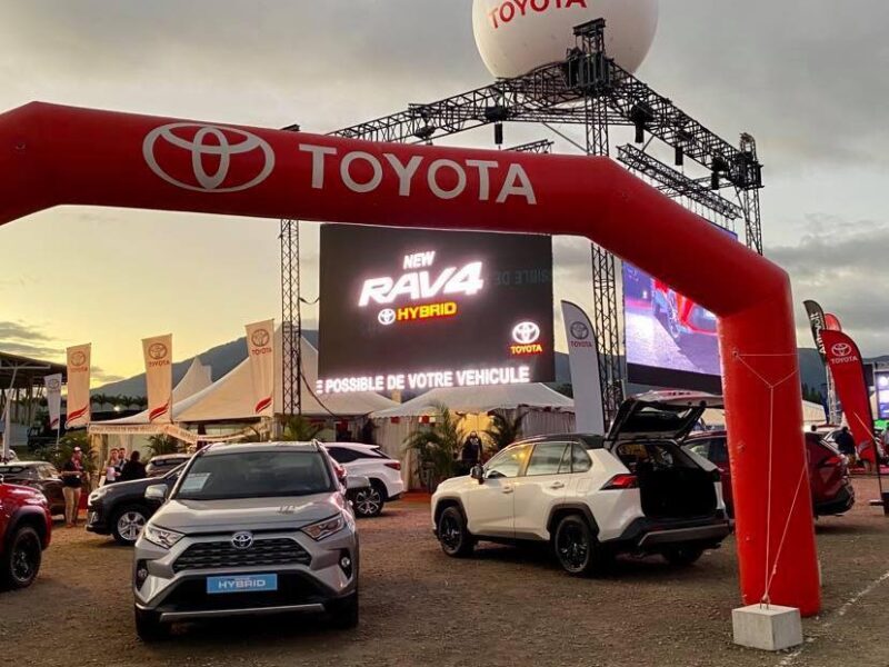 Photo prise sur le salon du 4x4 2021 en Nouvelle-Calédonie. Il s'agit de l'entrée du stand de Toyota. On y voit une arche rouge, plus de 5 voitures exposées ainsi que leurs écrans géants et leur ballon géant flottant au dessus du stand.