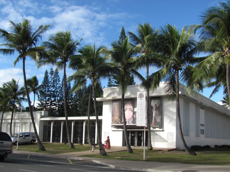 Photo de l'extérieur du musée de la Nouvelle-Calédonie avant sa rénovation. Plusieurs cocotiers son planter devant son entrée.