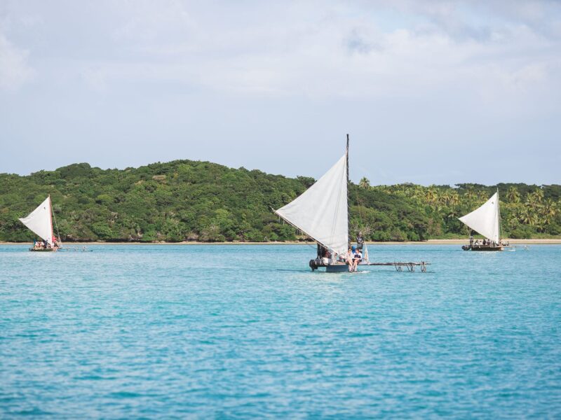 Photo de pirogues réalisant la traversée de la baie d'Upi à l'île des Pins en Nouvelle-Calédonie.